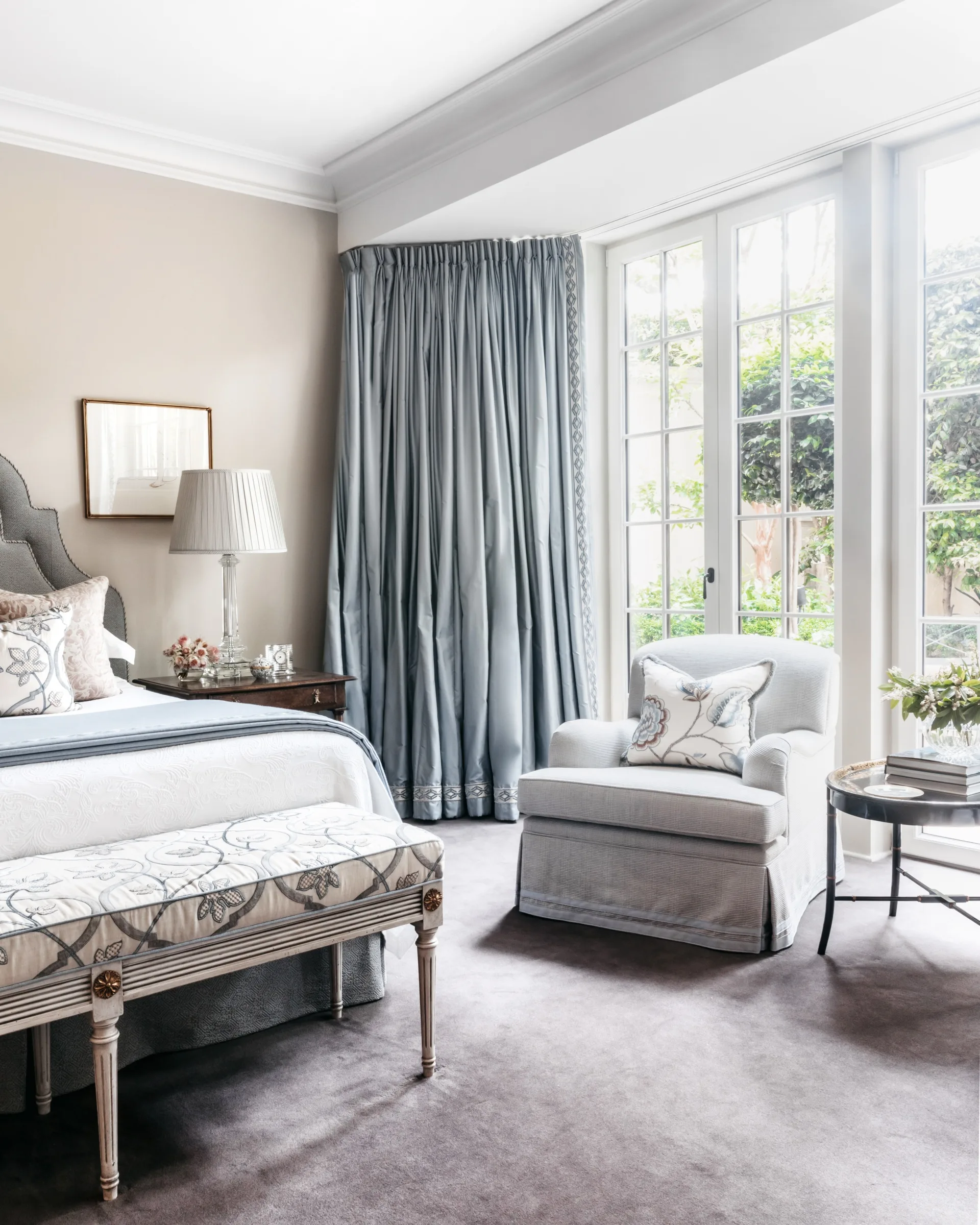 A classic style main bedroom with French-style doors, silk curtains and a grey bed.