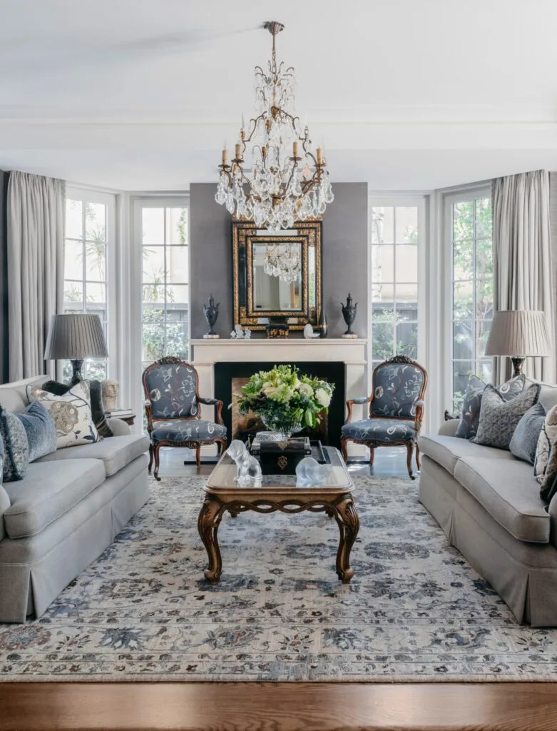 A classic sitting room with a glass chandelier and vintage-style furniture.