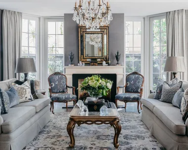 A classic sitting room with a glass chandelier and vintage-style furniture.
