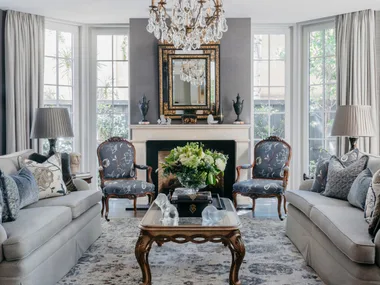 A classic sitting room with a glass chandelier and vintage-style furniture.
