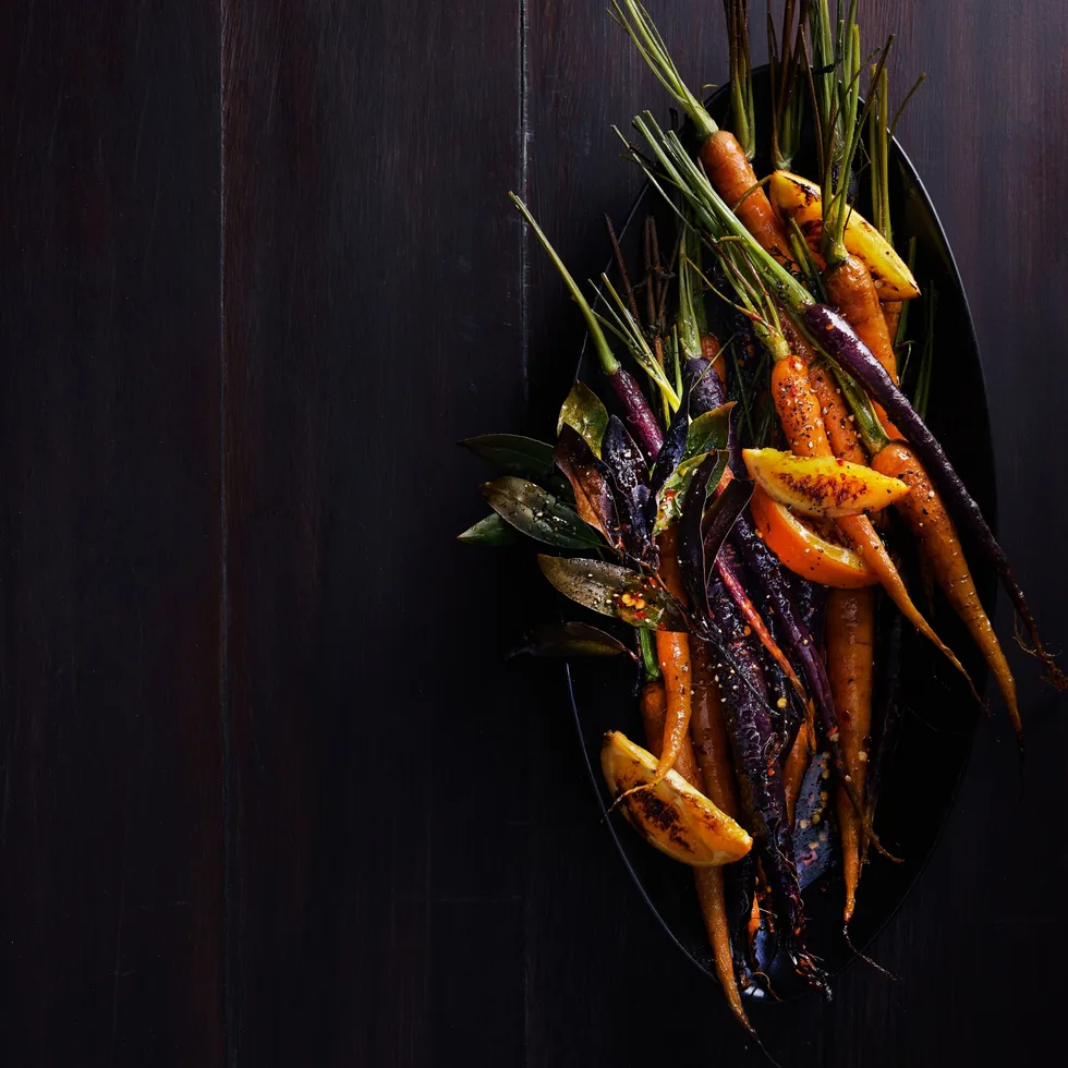 Gin and orange roasted carrots served on a table.