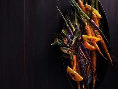 Gin and orange roasted carrots served on a table.