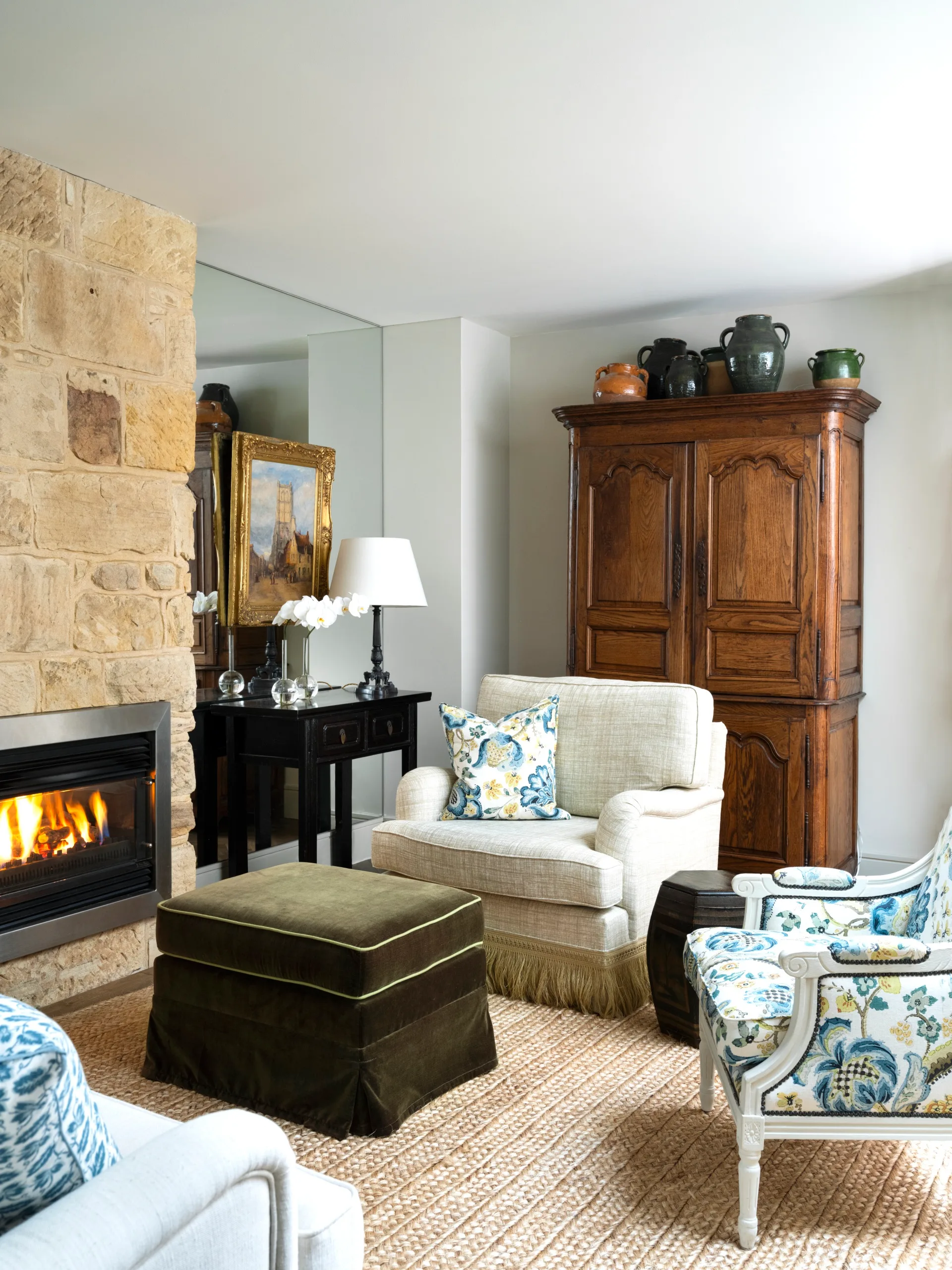 A heritage-style sitting room with a sandstone fireplace and antique furniture.