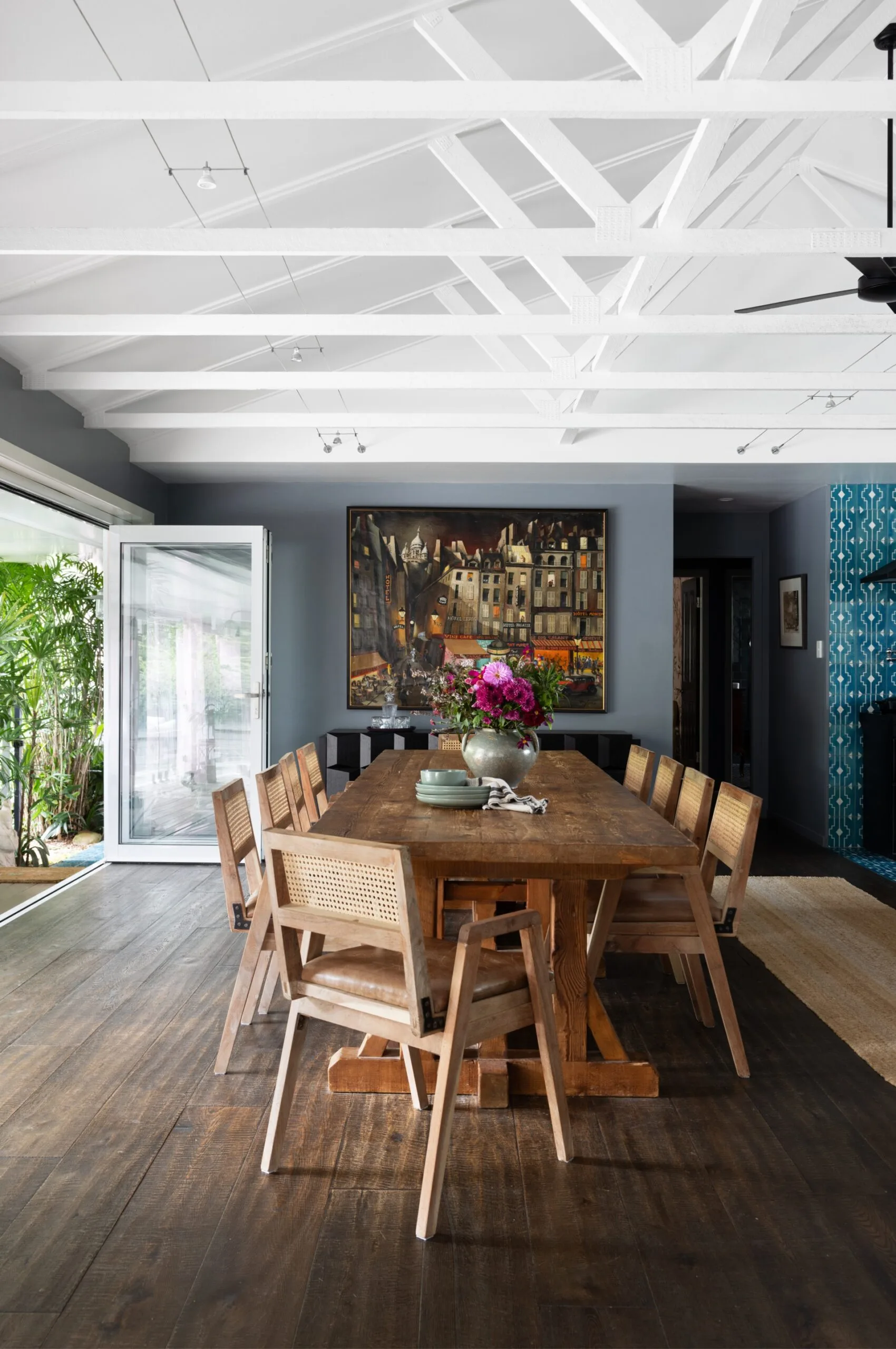 A dining area with dark timber floors , a long timber table and raised ceilings.