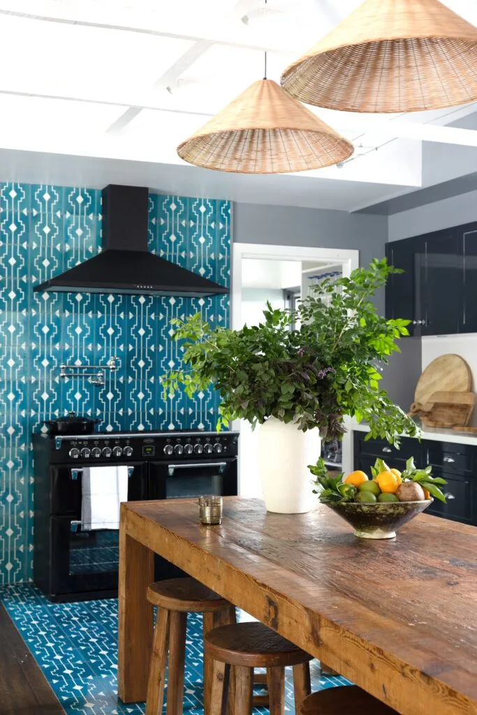 A European-style kitchen with blue mosaic tiles and a timber table.