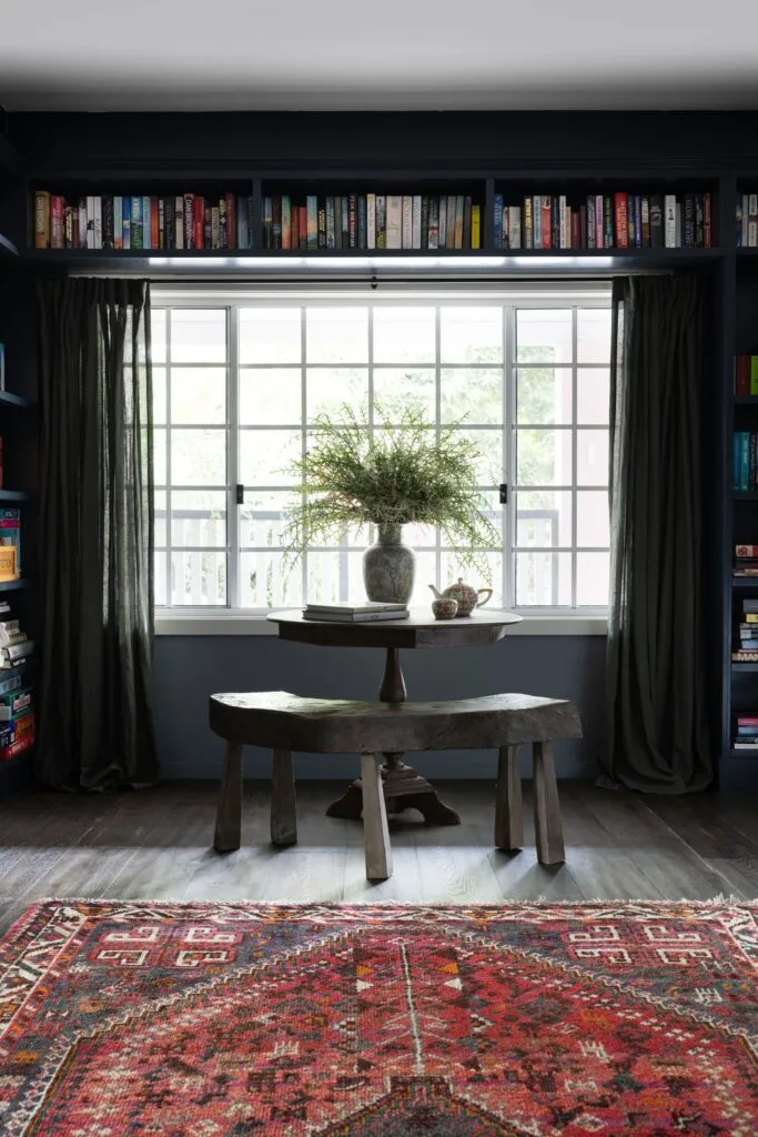 A library room with black-framed windows and vintage-style table.