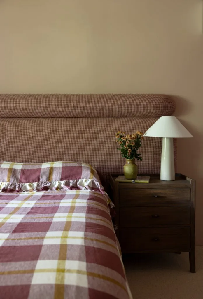 A main bedroom with a wicker-style bedhead and plaid linen.