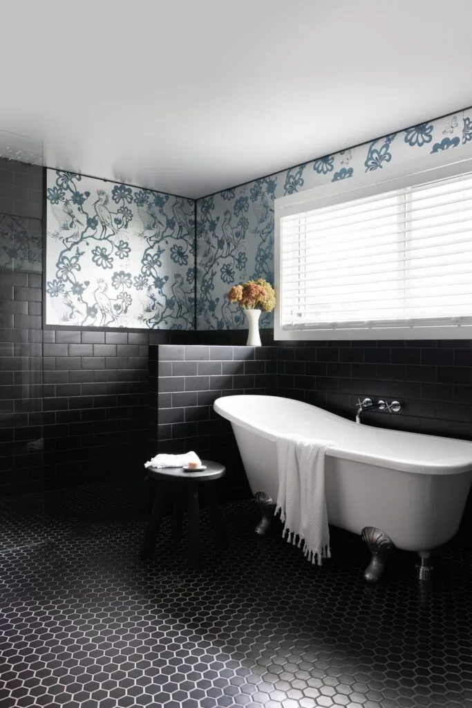 A main bedroom ensuite with a claw-foot bath, blue floral wallpaper and back tiles.