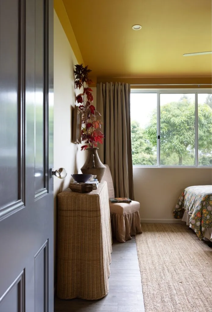 A yellow twin bedroom with a wicker console table.