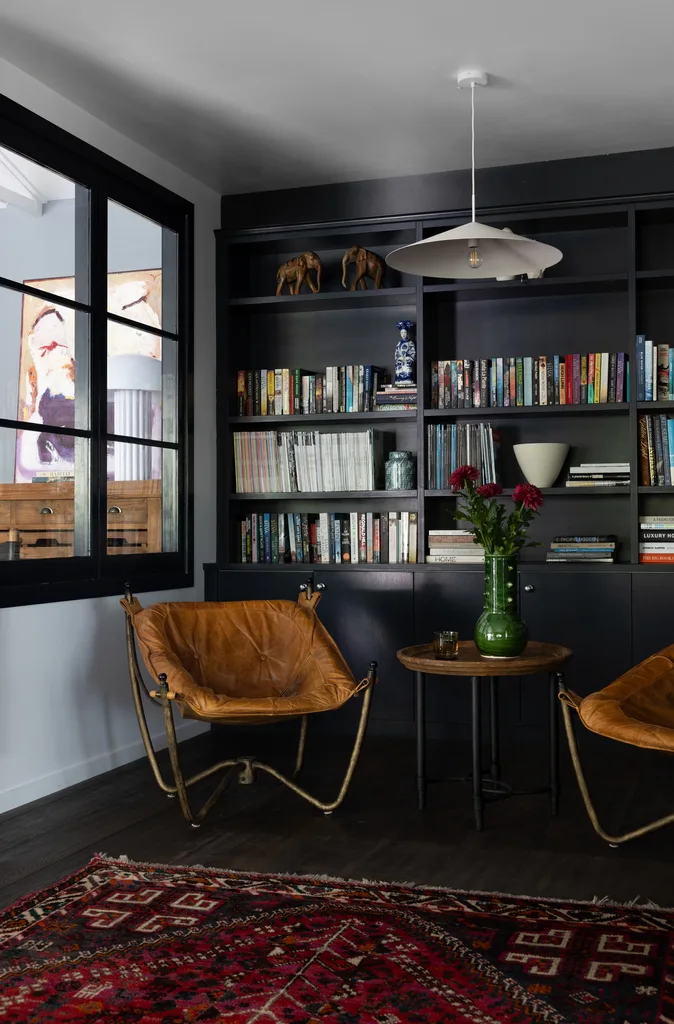 A sitting area with dark library shelves and two leather-style chairs.