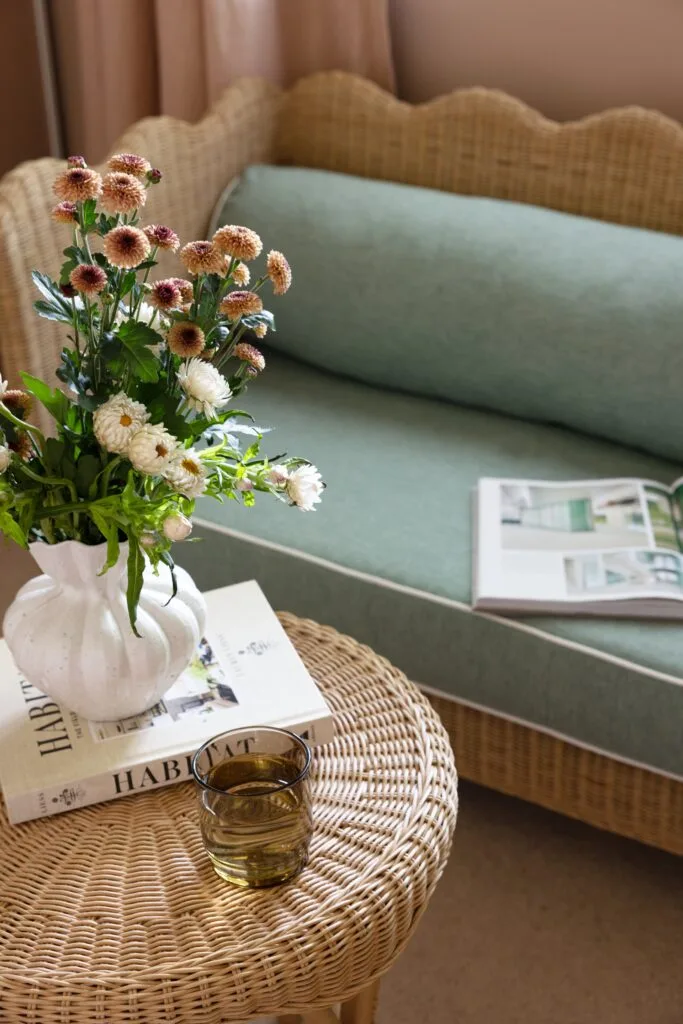 A wicker table and vase beside a wavy wicker bench.