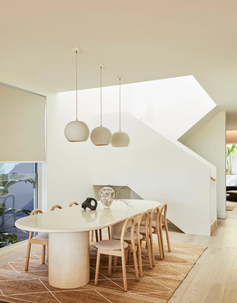 Darren Palmer's Bondi home dining area next to light-filled staircase.