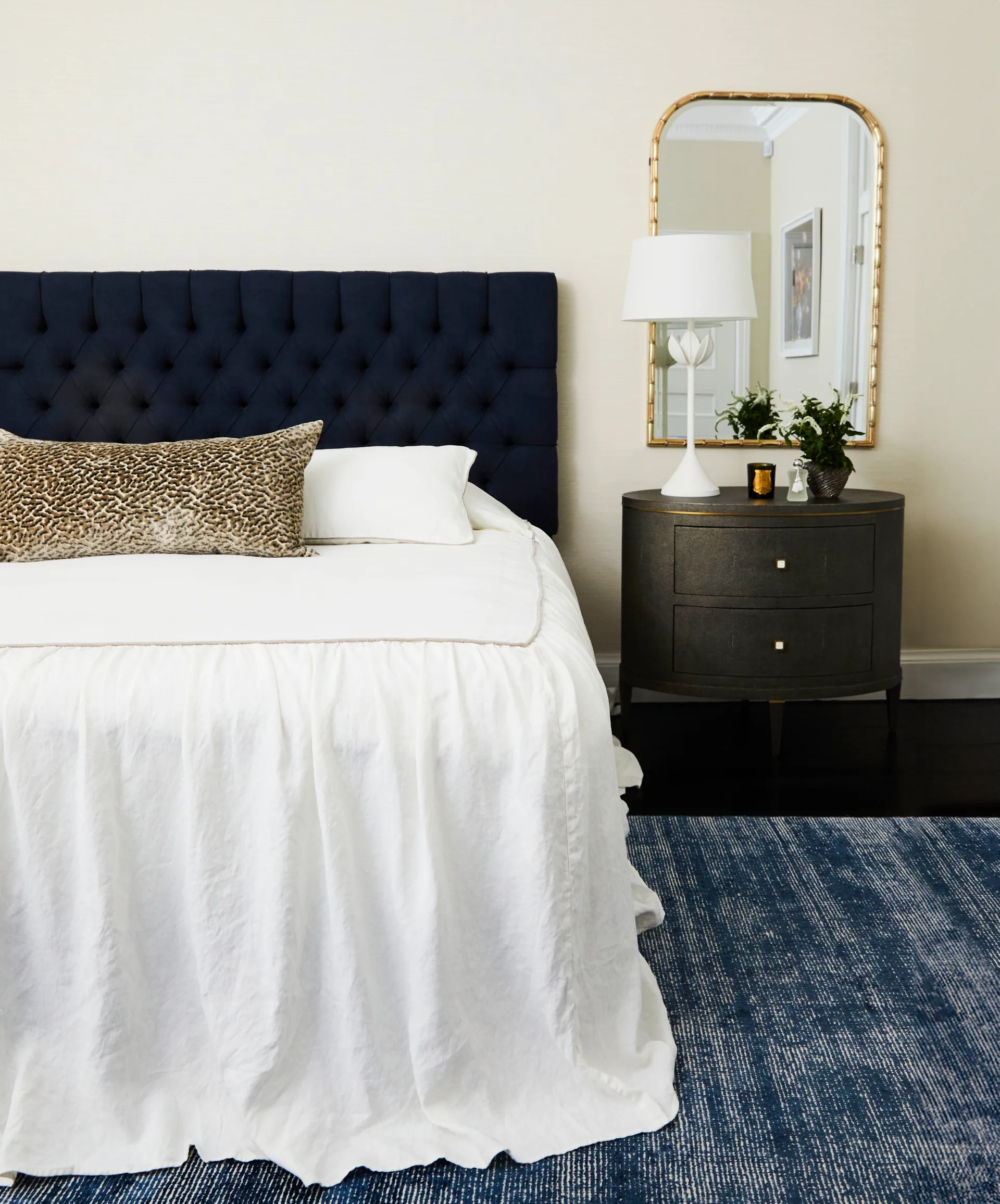 A main bedroom with a black bedhead and side table and white valance.