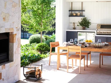An outdoor alfresco area flanked by a stone fireplace.