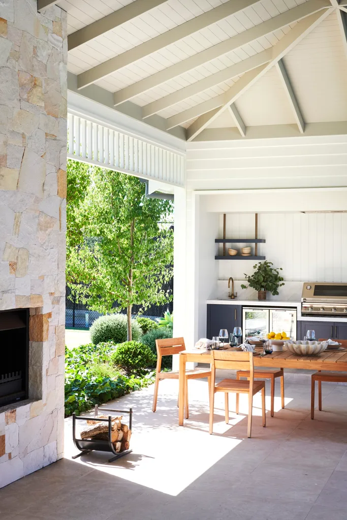 An outdoor alfresco area flanked by a stone fireplace.