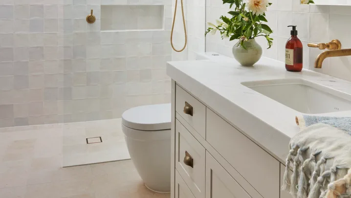 A classic all-white guest bathroom with gold tapware accents.