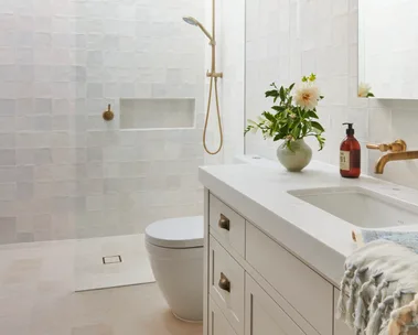 A classic all-white guest bathroom with gold tapware accents.
