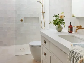 A classic all-white guest bathroom with gold tapware accents.