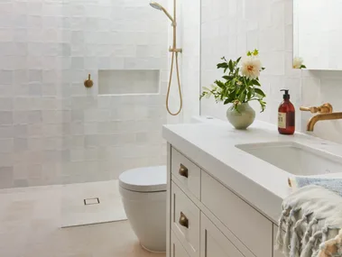 A classic all-white guest bathroom with gold tapware accents.