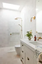 A classic all-white guest bathroom with gold tapware accents.
