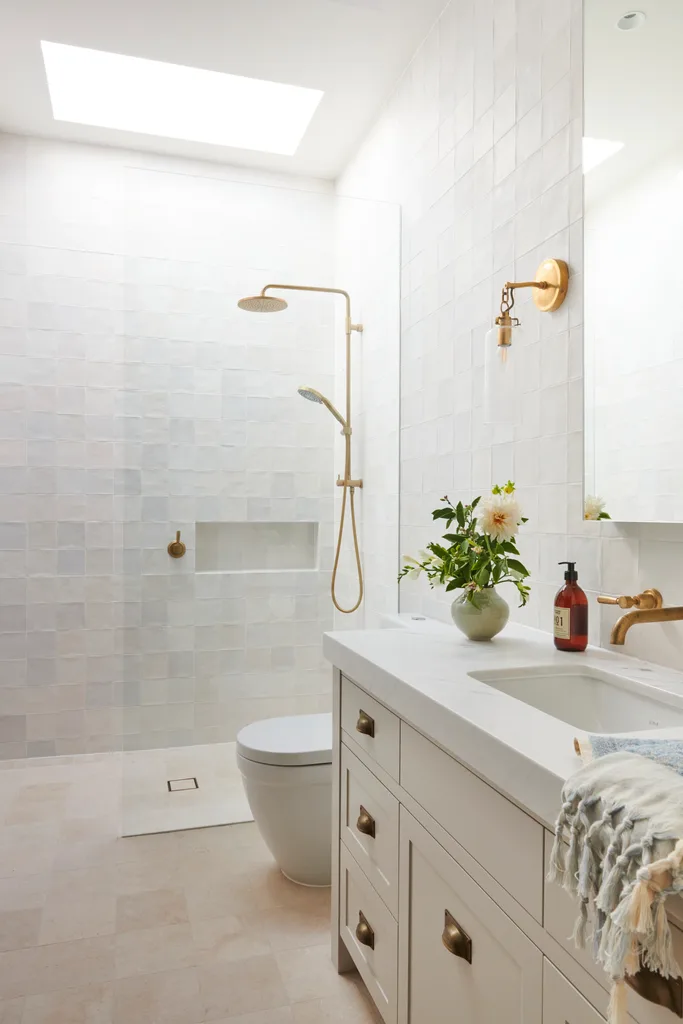 A classic all-white guest bathroom with gold tapware accents.