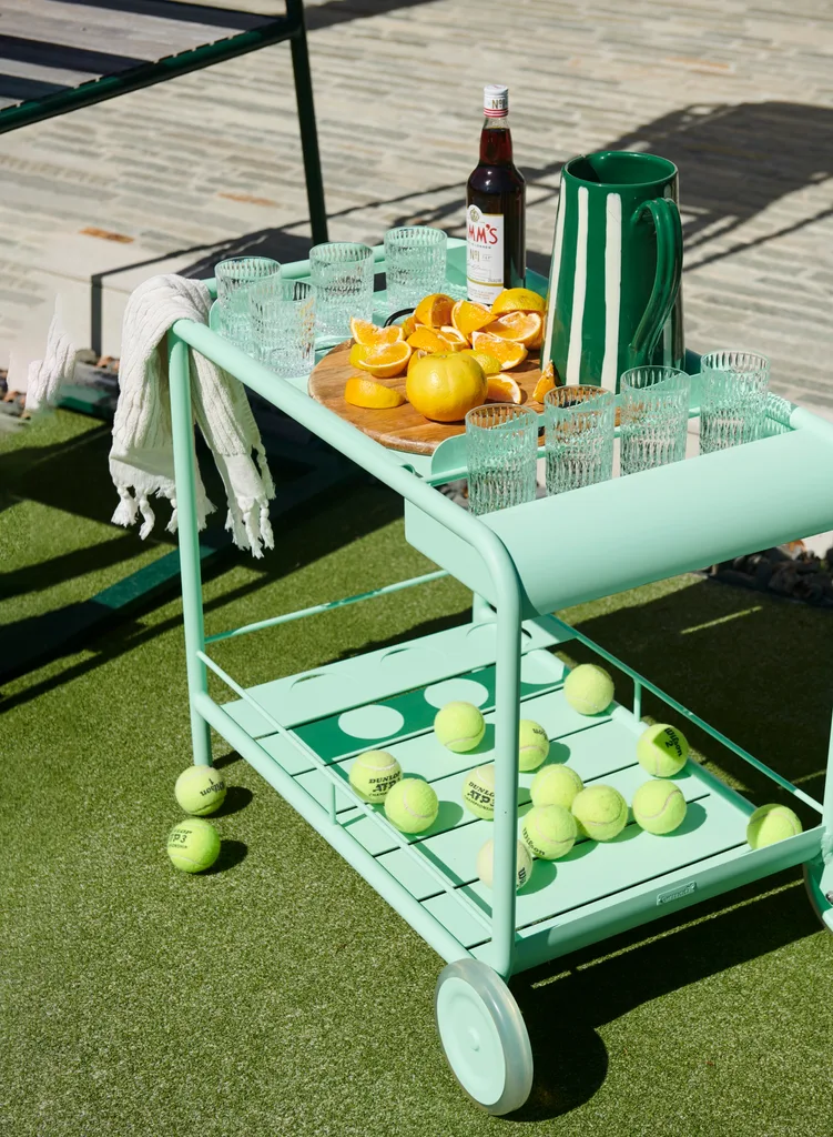 A mint green bar cart on a tennis court.