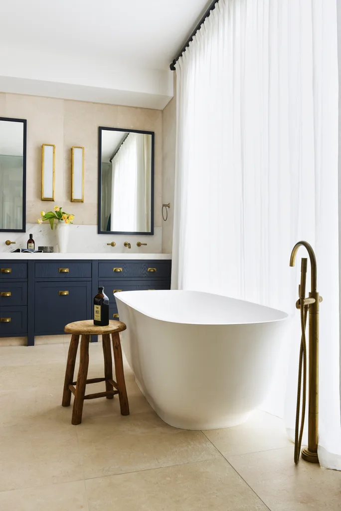 An ensuite with a freestanding bath and a navy double vanity.