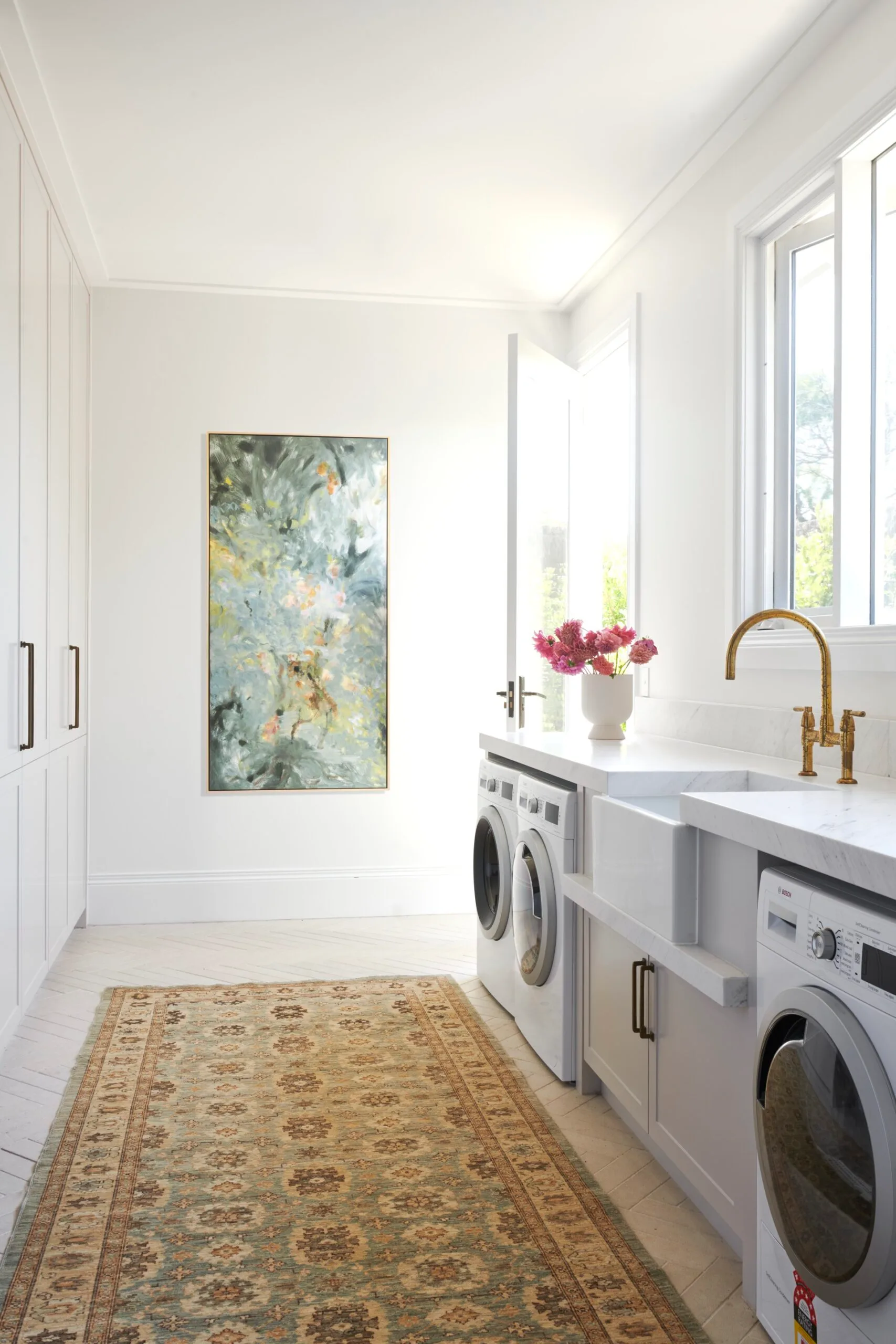 An all-white laundry room with a vintage-style rug runner.