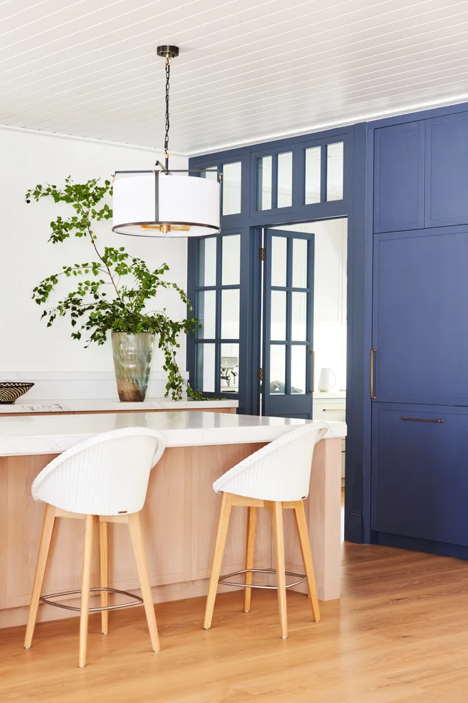 Two rounded white bar stool beside blue French kitchen doors.