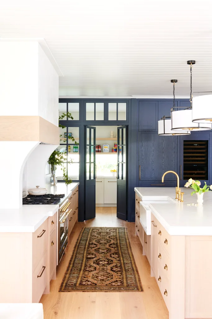 A stylish blue and white kitchen with a vintage-style rug runner.