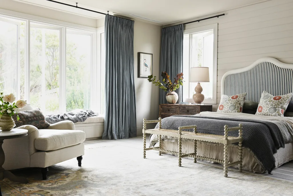 A classically styled main bedroom with blue accents and a window seat.