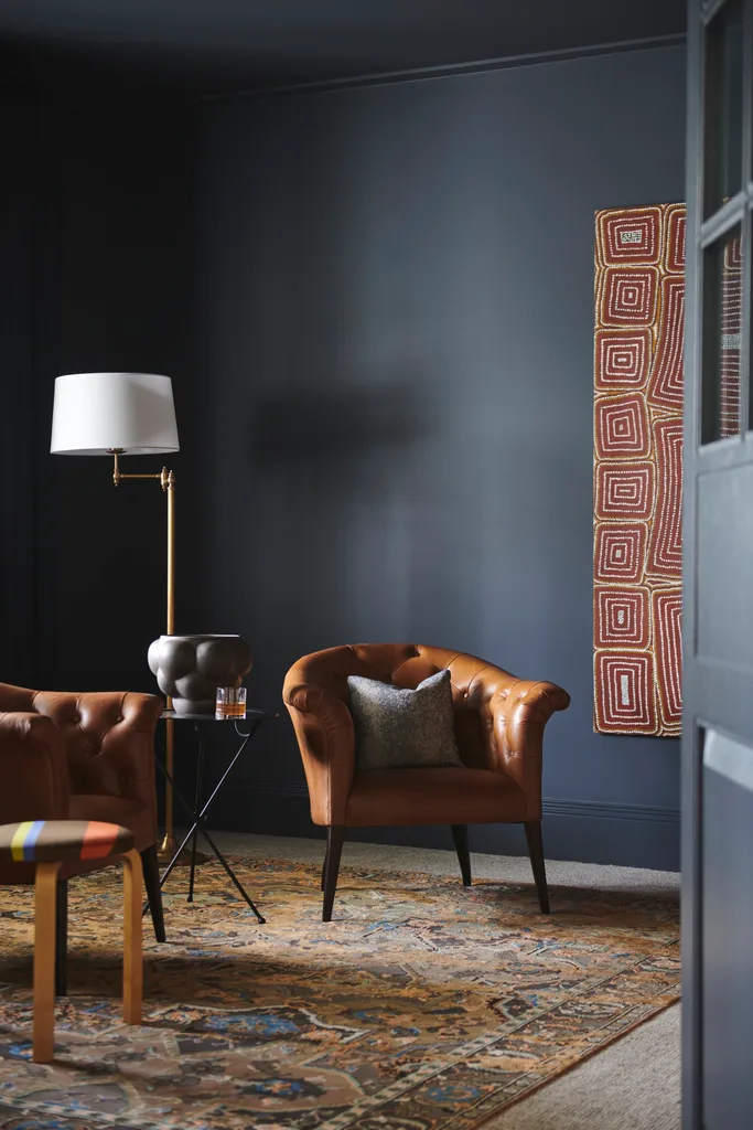 A navy study with two leather armchairs and a red swirl artwork.