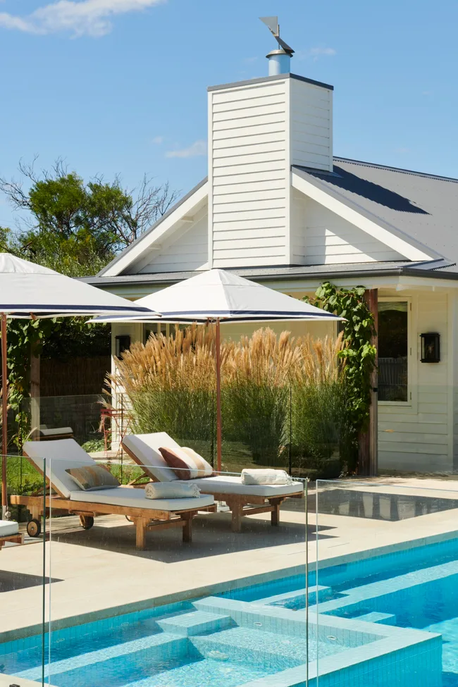 Two white pool loungers and parasols.