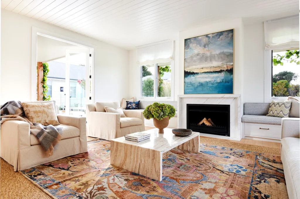 A vibrant sitting room with a marble fireplace, large abstract artwork and patterned rug.
