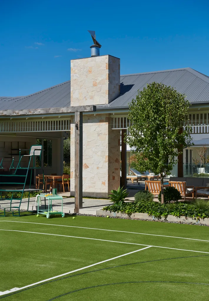 A tennis court leading to a green alfresco area.