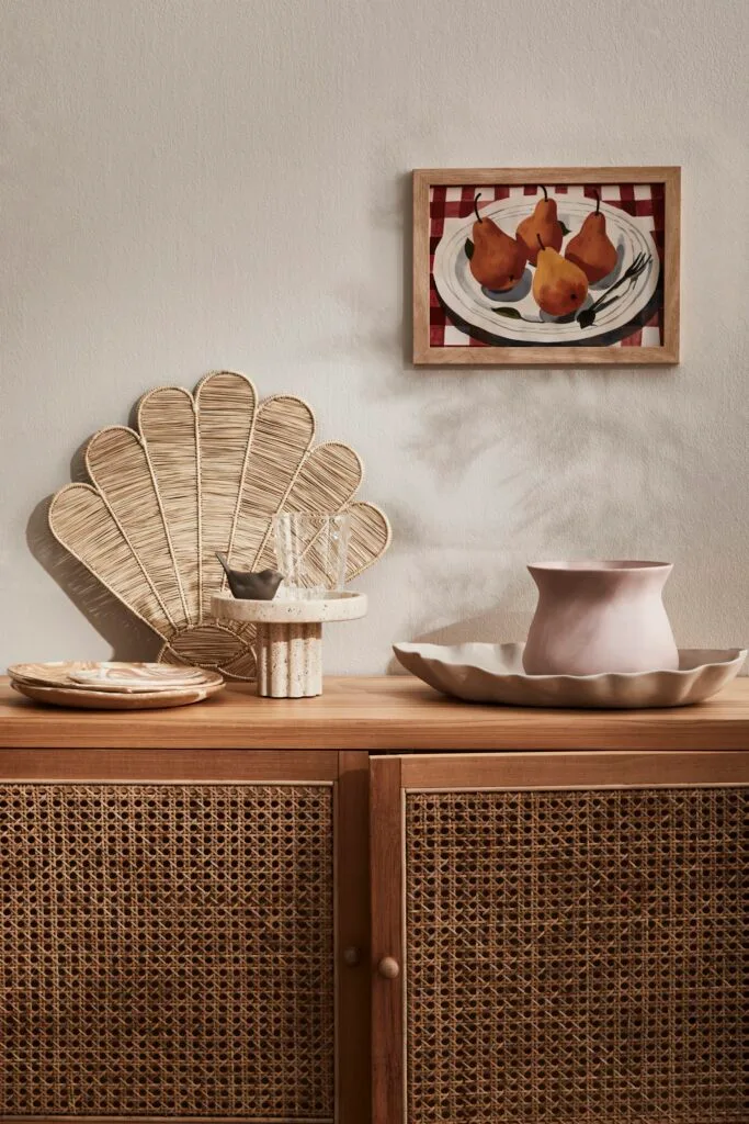 A rattan console with decorative vases and bowls on top.