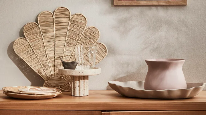 A rattan console with decorative vases and bowls on top.