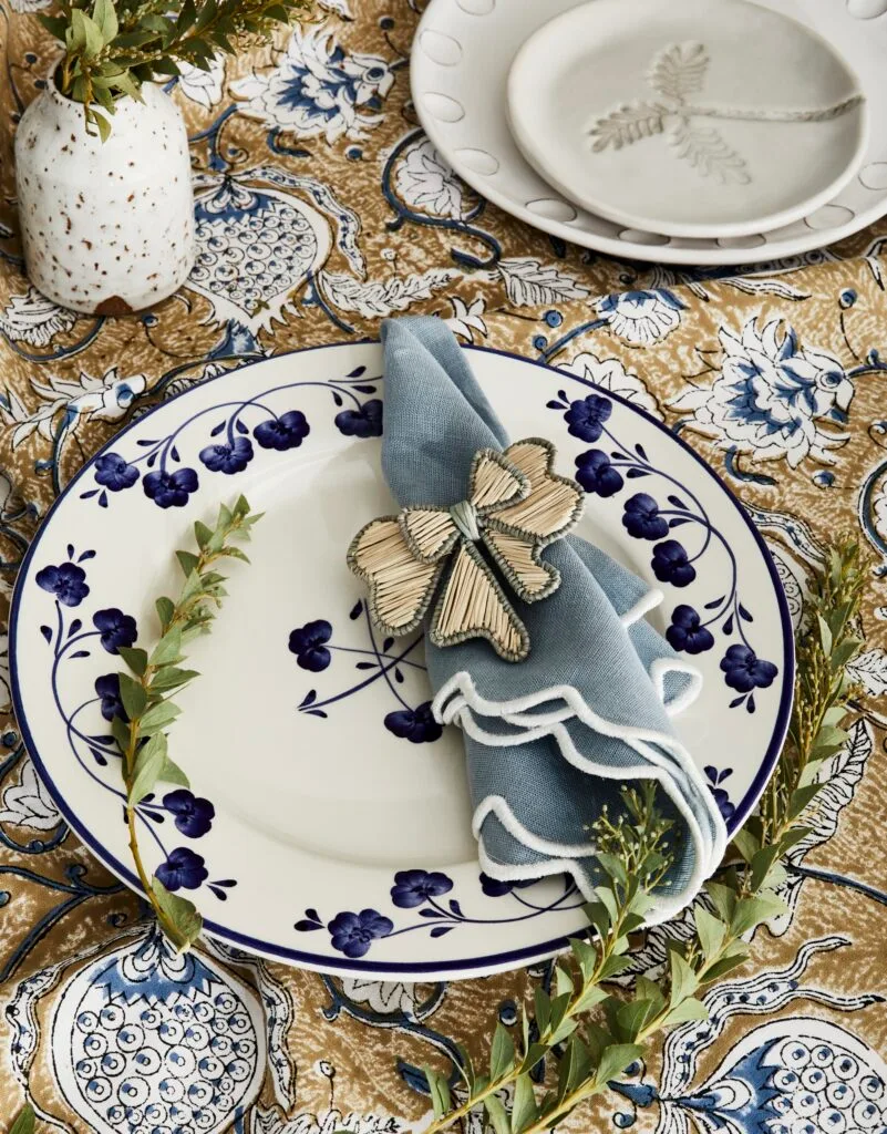 A table setting with a blue floral plate and scalloped napkin.