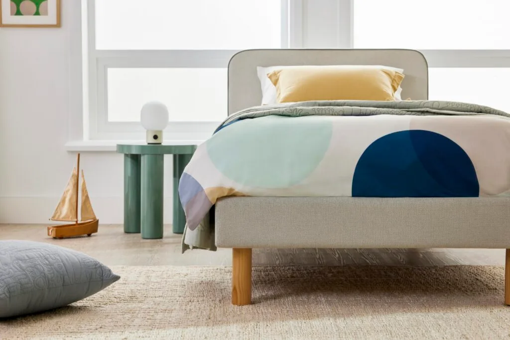 A single bed in a children's bedroom with polka dot bedding.