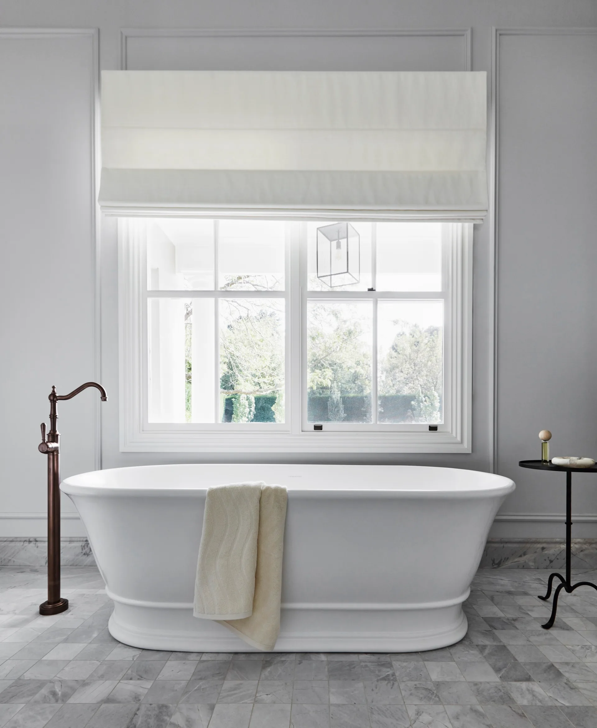 A vintage-style freestanding bath below a window.