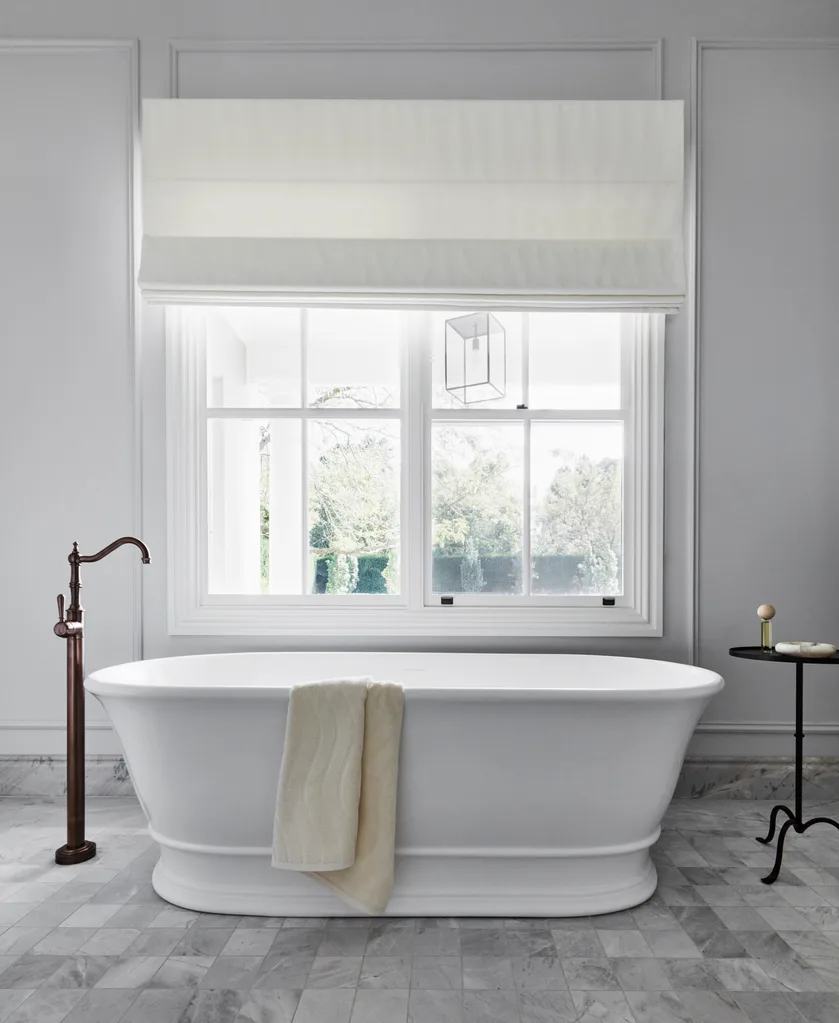A vintage-style freestanding bath below a window.