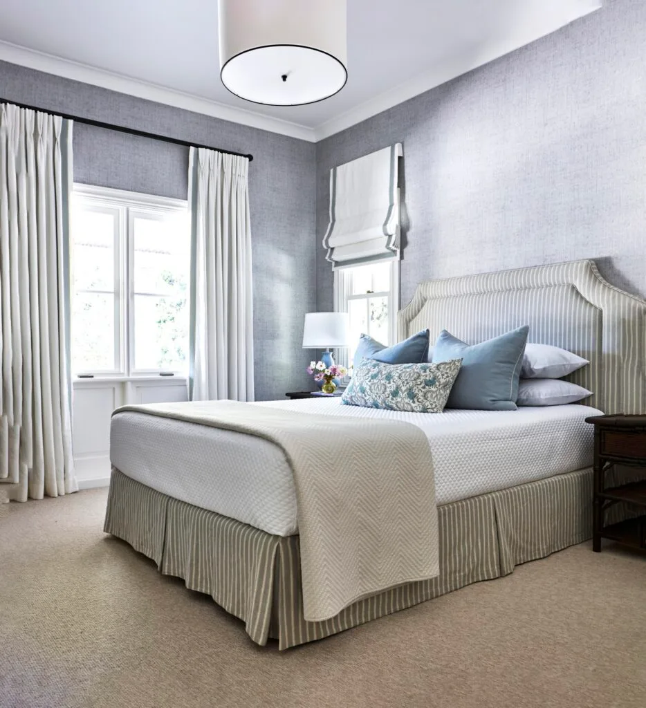 A country-style guest bedroom with a striped bed and classic upholstery.