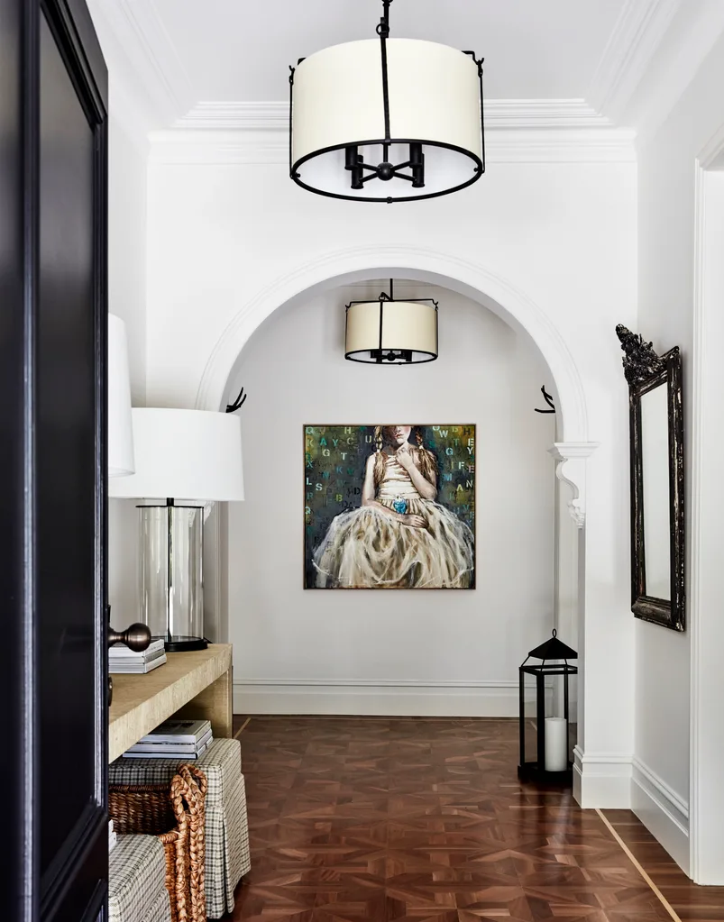 A hallway with vintage furniture and a large art portrait.