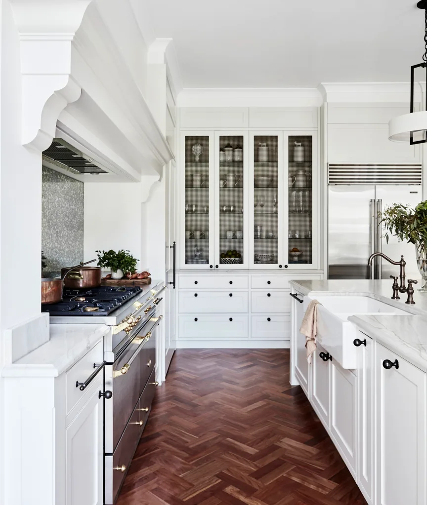 A country-style kitchen with shaker cabinets, a freestanding oven and an island with a farmhouse ink.