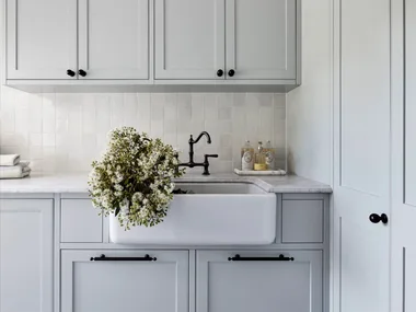 A classic grey country laundry with a farmhouse sink and shaker cabinets.