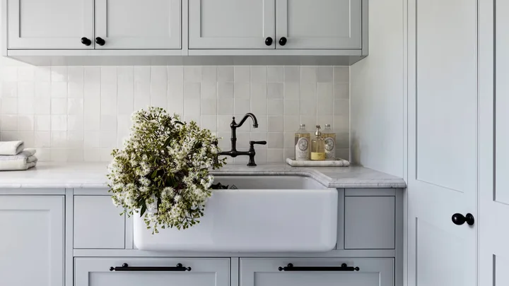A classic grey country laundry with a farmhouse sink and shaker cabinets.