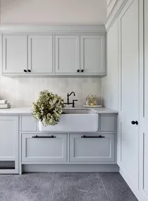 A classic grey country laundry with a farmhouse sink and shaker cabinets.