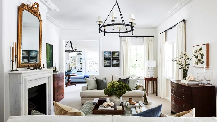A country-style living room with a marble fireplace, vintage mirror and furniture.