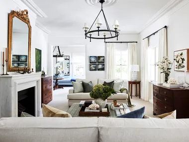 A country-style living room with a marble fireplace, vintage mirror and furniture.