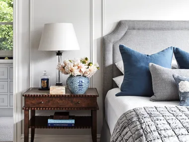 A country style bedroom with wainscoting and vintage-style furniture.